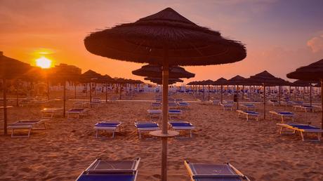 Wassertemperatur Rimini: Liegestühle und Sonnenschirme am Strand von Rimini bei Sonnenuntergang