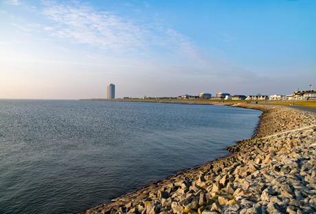 Wassertemperatur Büsum: Damm mit Nordsee und Hochhaus von Büsum am Horizont