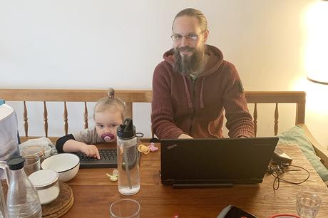 Ein Kind und ein Mann mit Laptop am Esstisch