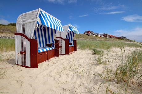 Wassertemperatur Amrum: Strandkörbe auf Sandstrand mit Dünengras, im Hintergrund die Häuser von Wittdün