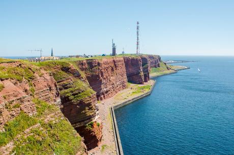 Wassertemperatur Helgoland: Blick von dem Aussichtspunkt an der Langen Anna auf die Buntsandsteinklippen des Oberlands mit Leuchtturm und Sendemast, links die Kirchturmspitze von St. Nicolai
