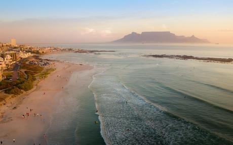 Wassertemperatur Südafrika: Blick aus der Luft vom Strand Big Bay Beach nach Süden auf Kapstadt und den Tafelberg bei Sonnenuntergang