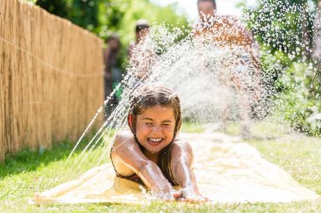 Mädchen rutscht Wasserutsche im Garten hinunter