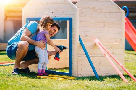 Vater und Tochter bauen gemeinsam ein Garten Spielhaus auf.