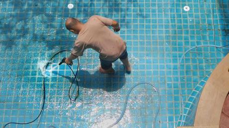 Mann reinigt den Pool mit einem Druckreiniger