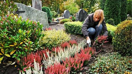 Eine Frau bepflanzt ein Grab.