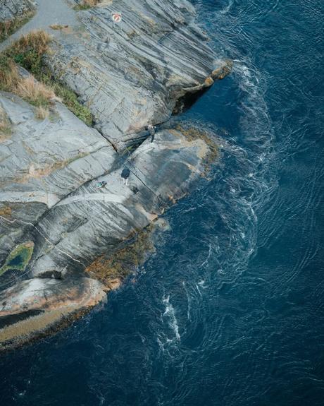 Felsige Küste mit blauen Meereswellen, die gegen die Felsen plätschern, von oben gesehen.