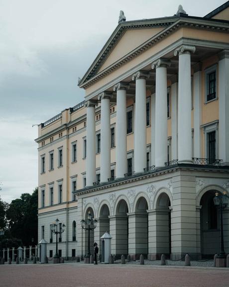 Ein prächtiges neoklassizistisches Gebäude mit hohen weißen Säulen und gewölbten Fenstern unter einem bewölkten Himmel.