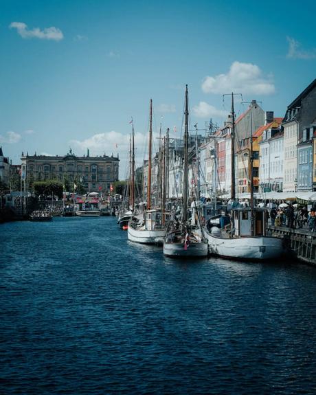 Hölzerne Segelboote legten an einem Kanal an, der von bunten Gebäuden unter blauem Himmel gesäumt war.