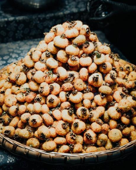 Ein großer Haufen stacheliger, runder Früchte oder Samen, die in einem geflochtenen Korb präsentiert werden.