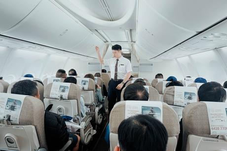 Ein Flugbegleiter weist die Passagiere in der Flugzeugkabine in die Sicherheitsmaßnahmen ein.