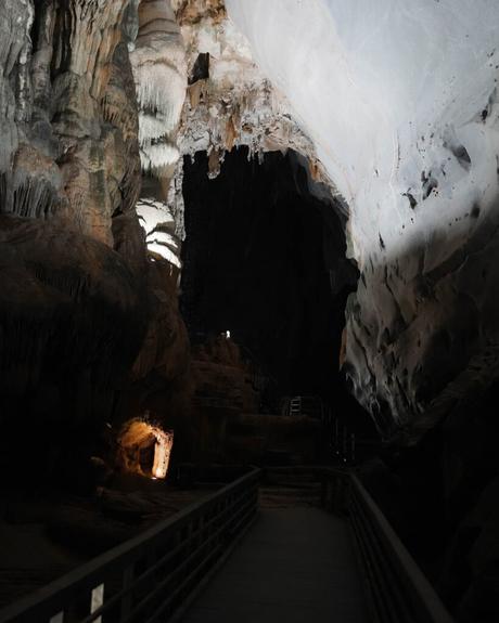 Ein schwach beleuchteter Gang im Inneren einer großen Höhle mit strukturierten Felswänden und einer hohen Decke.