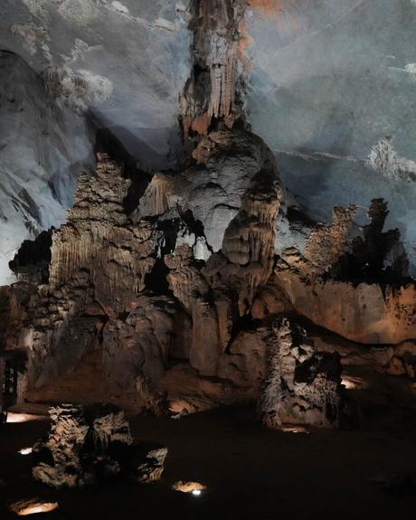 Zerklüftete Felsformationen und Stalagmiten in einer schummrigen Höhle mit strukturierten Wänden und Decken.