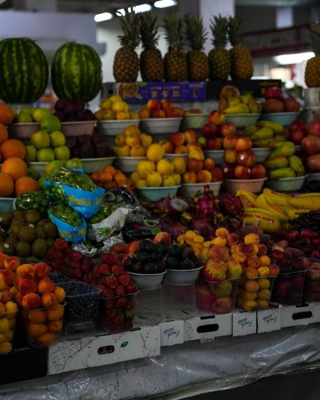 Ein Obststand auf dem Markt mit Ananas, Wassermelonen, Äpfeln, Bananen, Erdbeeren und anderem Obst.