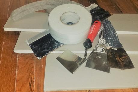 Drywall and tools. Various sized cuts of 1/2 inch drywall with tools for maintenance and installation.