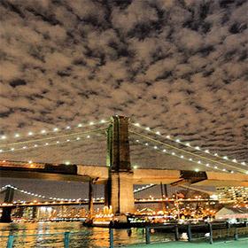 New York Brooklyn Bridge in der Nacht mit der Washington Bridge im Hintergrund