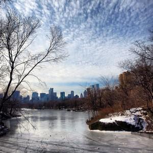 Central Park New York with frozen lake and Manhattan Skyline and great clouds