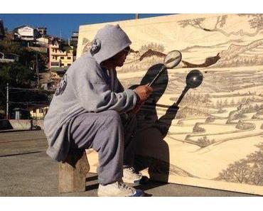 Künstler brennt mit Lupe und Sonne Bilder in Holz