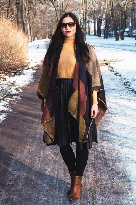 Kleidermädchen präsentiert ein winterliche Outfit-Kombination mit Cape und Faltenrock. Mit Rollkragenpullover von asos, Rock von Mango, Stiefeletten von Dressforless, Cape von Topshop und Sonnenbrille von Ralph Lauren.