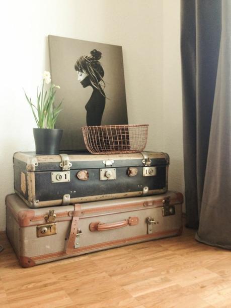 Juniqe Print fürs Wohnzimmer auf Vintage Koffern mit einer Kupferschale und Frühlingsblumen