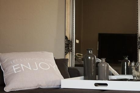 Kissen mit ENJOY-Schriftzug und das Deko-Tablett auf dem Loungesofa