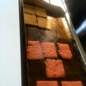 Grill mit quadratischen Fleischfrikadellen und Toastbrot